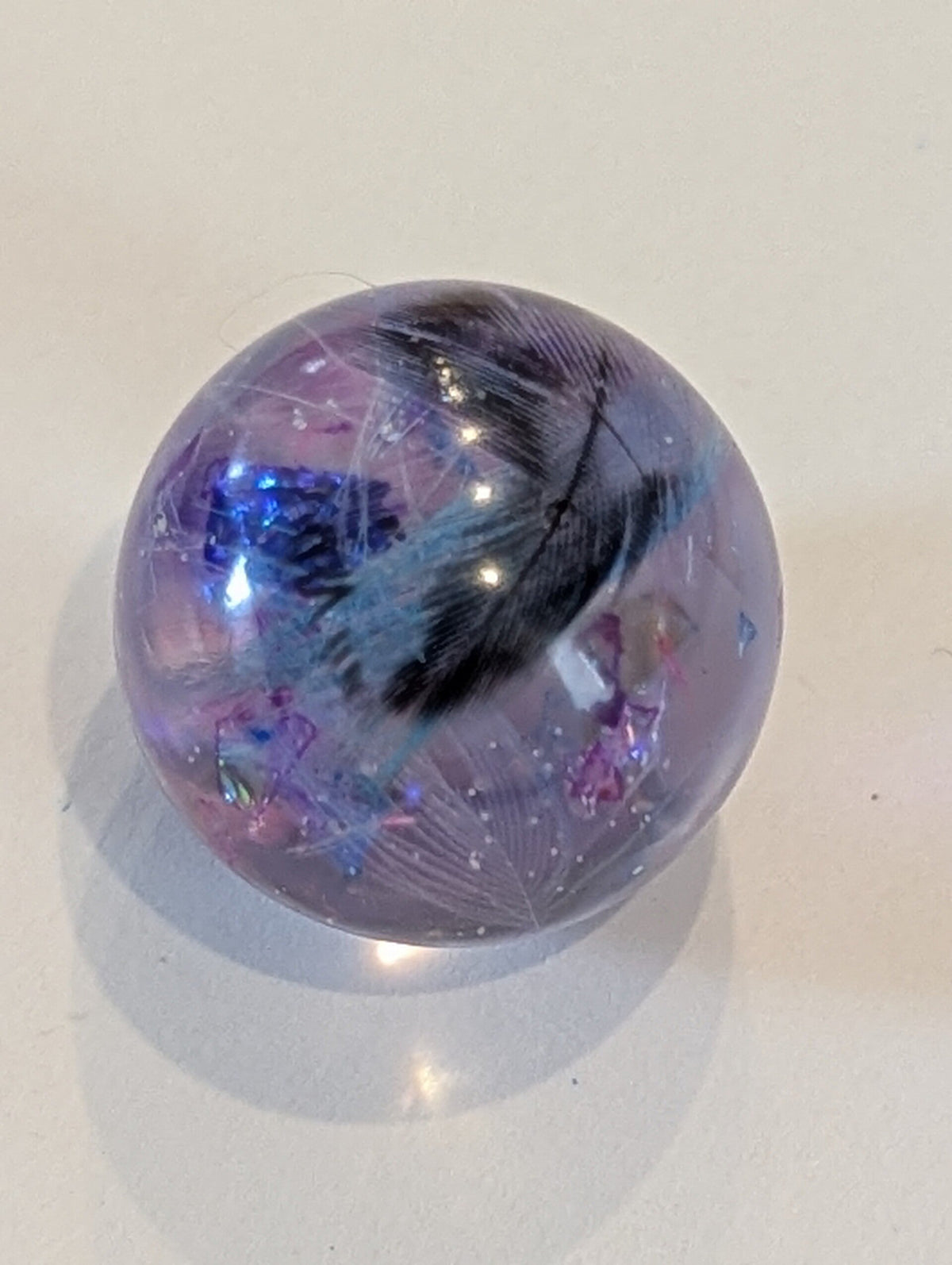Glasperle mit Vogelfeder